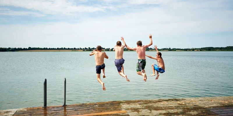 Jungs springen vom Badesteg in den See